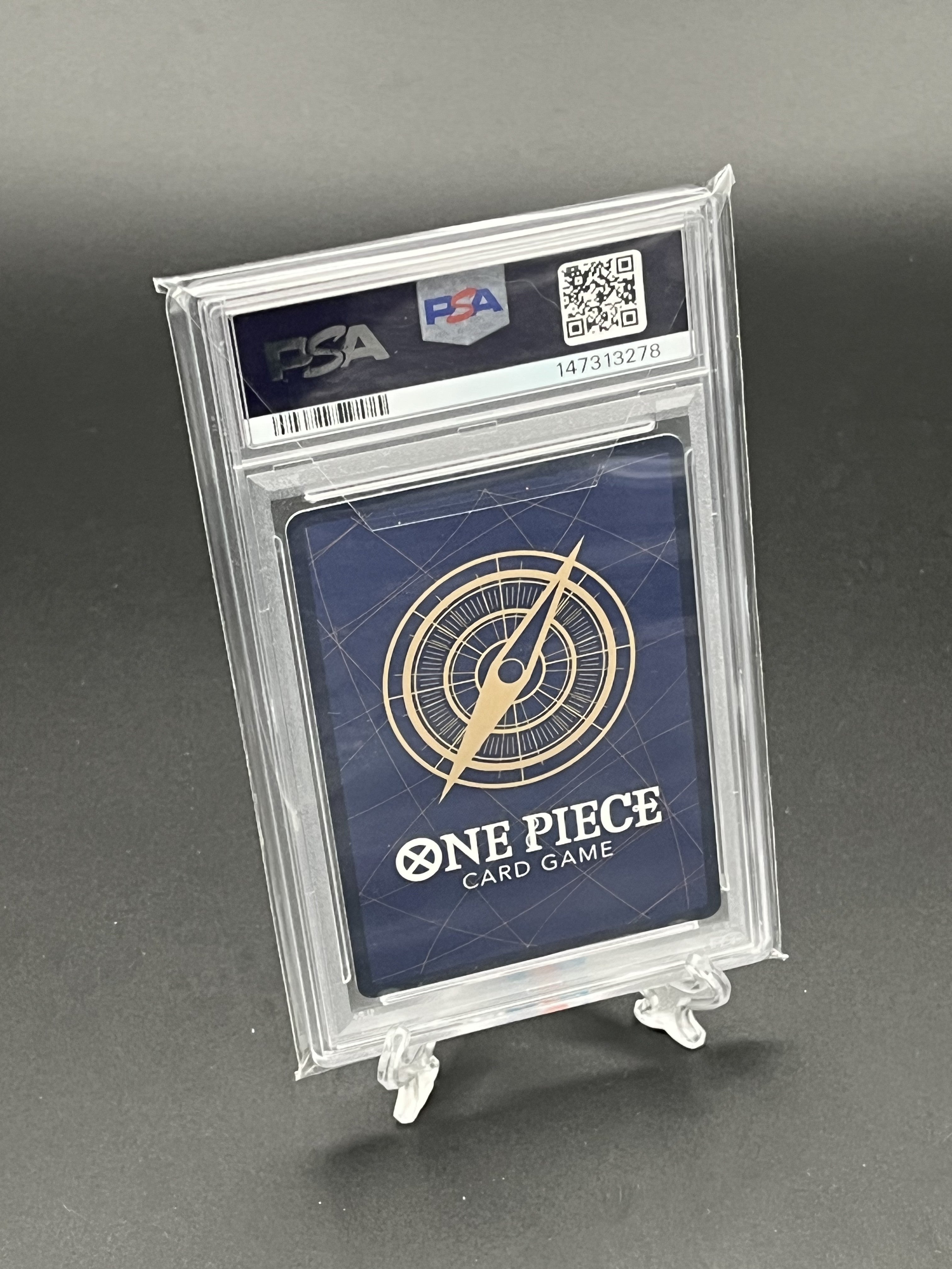 One Piece Card Game card in a PSA holder on a gray background