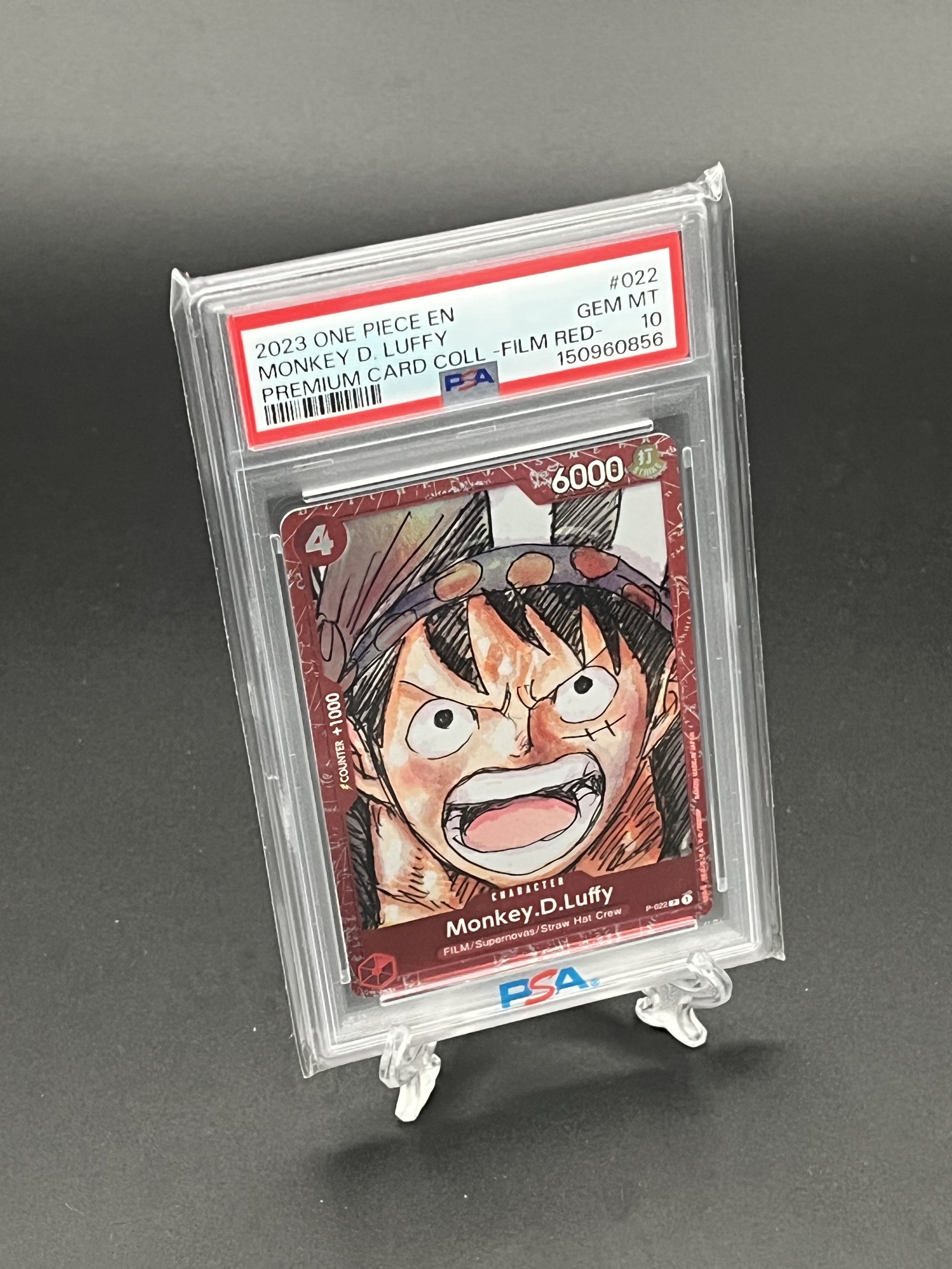 Trading card of Monkey D. Luffy from One Piece in a PSA holder on a gray background